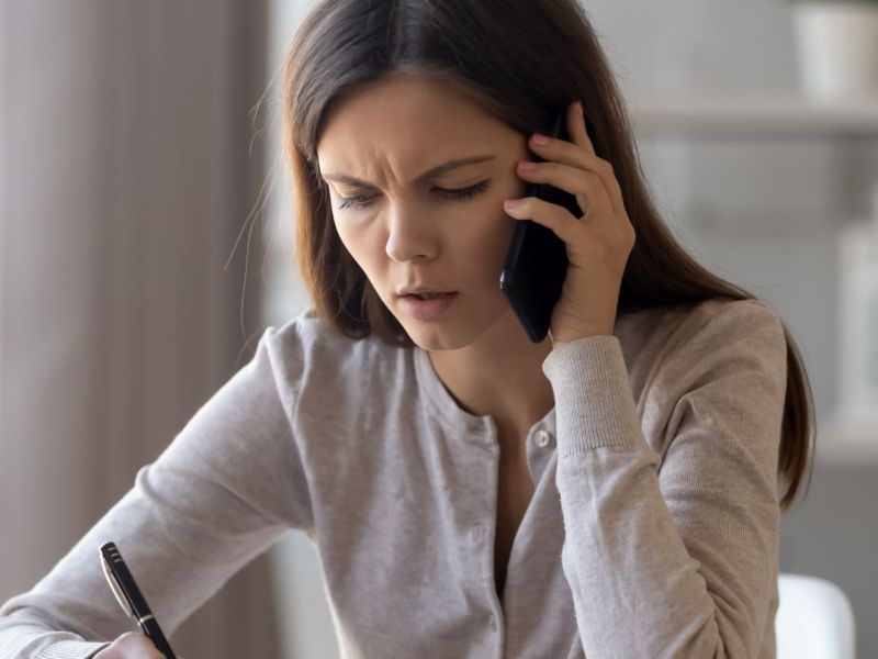 Frau misstrauisch am Telefon..