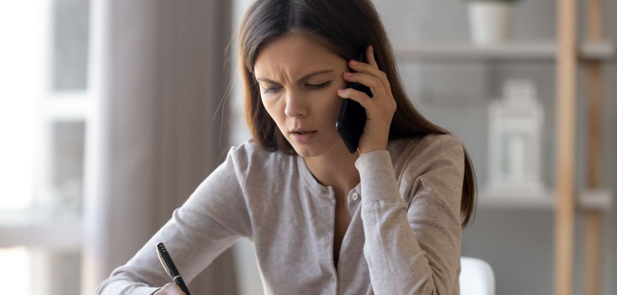 Frau misstrauisch am Telefon..