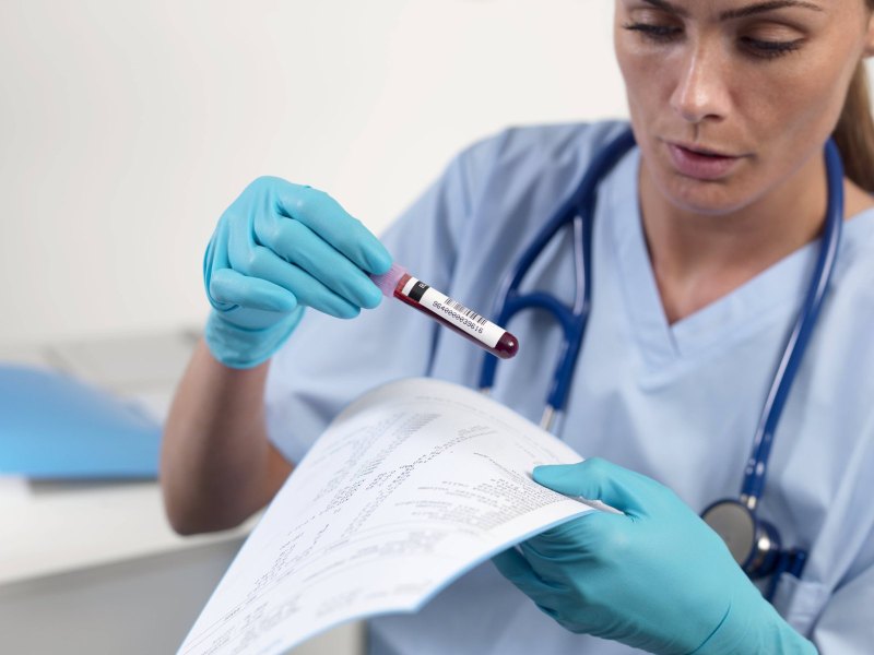 Eine Ärztin hält eine Ampulle mit Blut darin in der Hand.