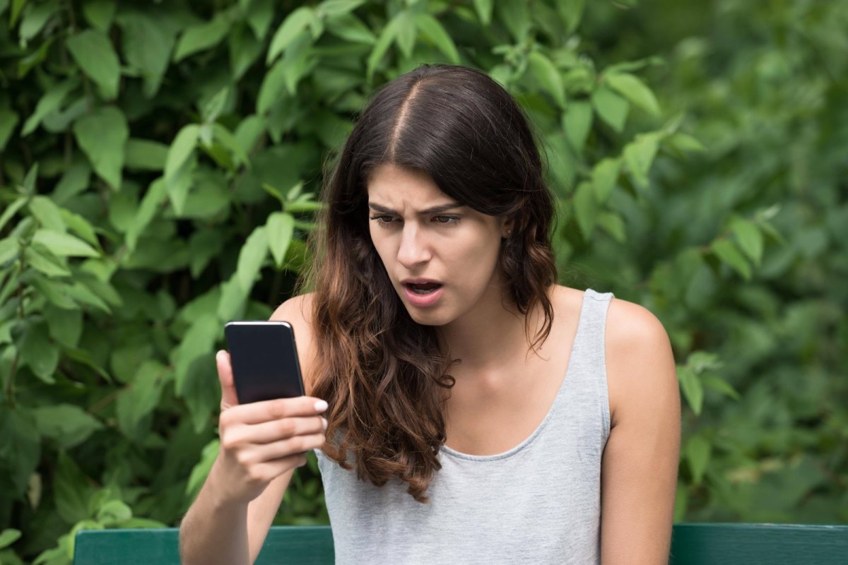 Frau regt sich über ihr Smartphone/ ihren Handy-Akku auf.