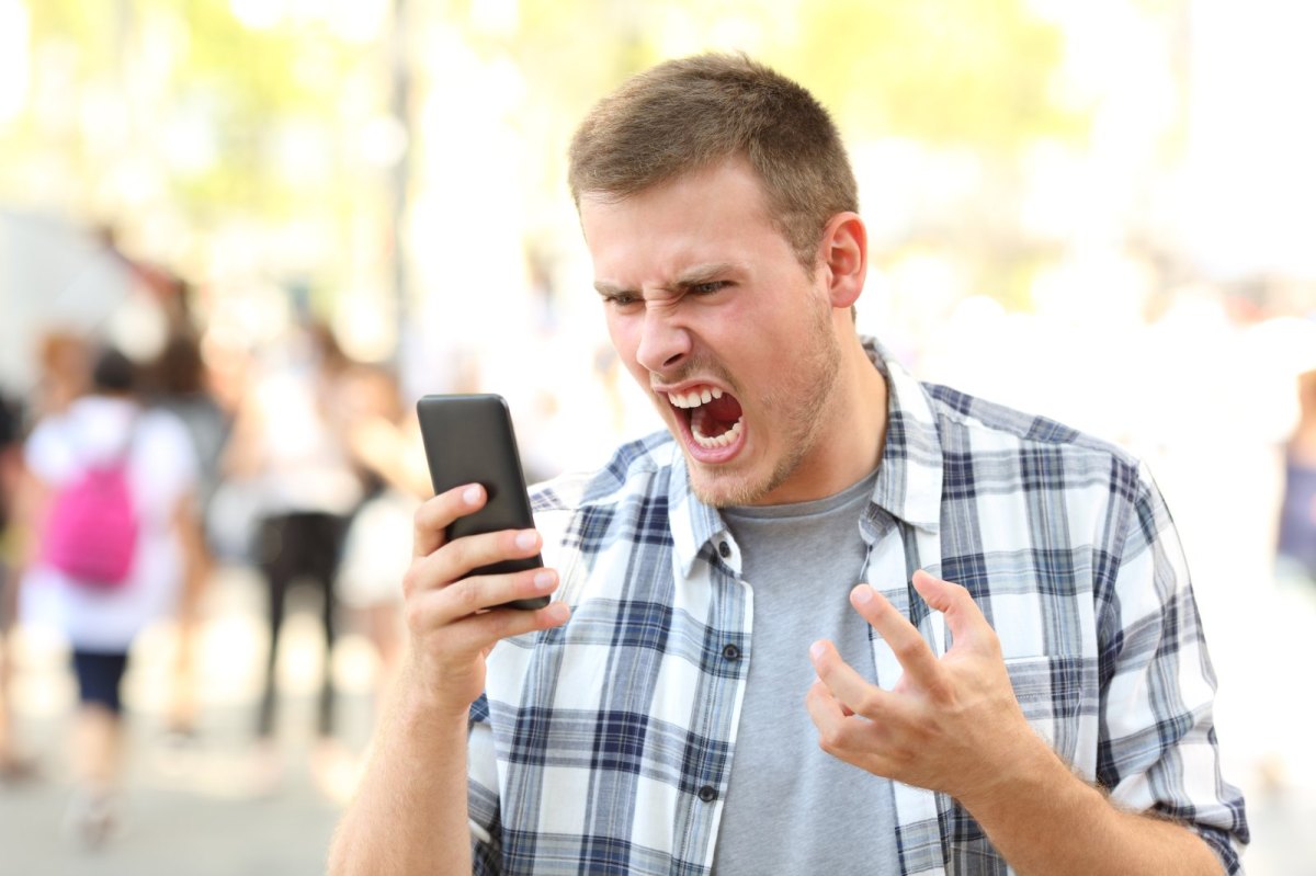 Mann beugt sich wütend übers Handy