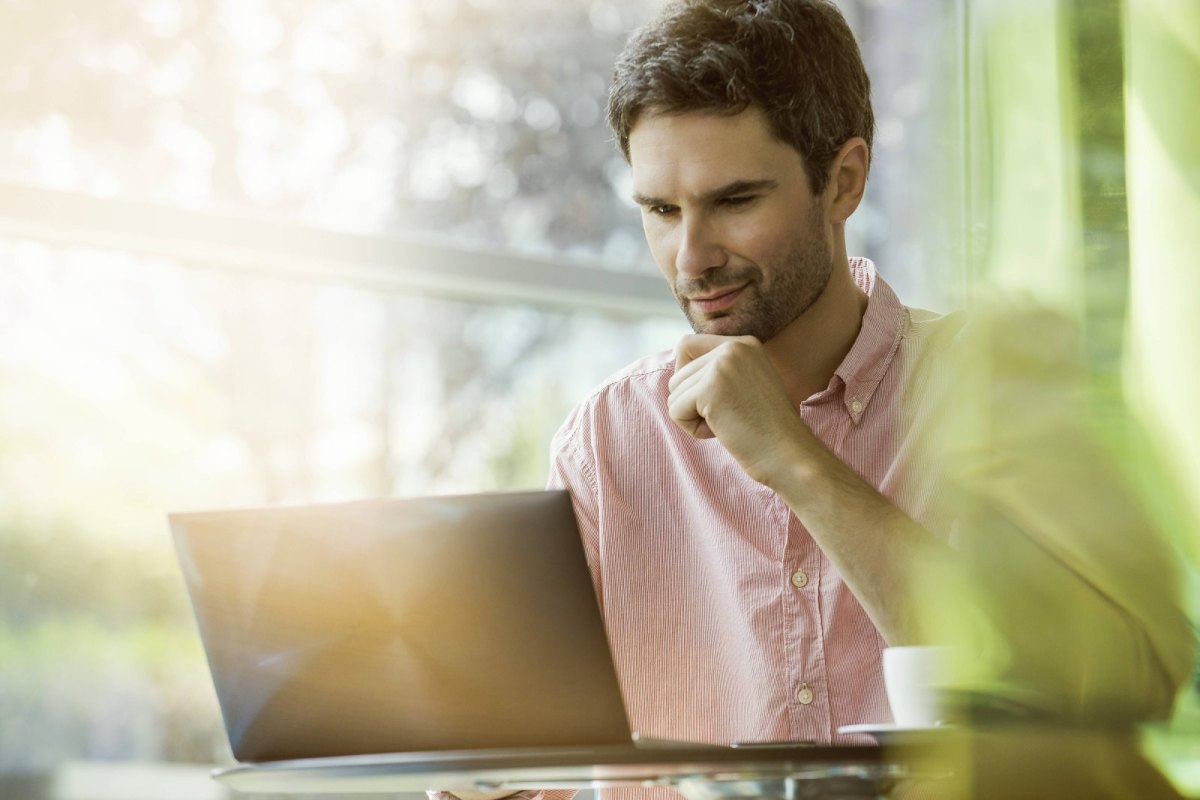 Mann sitzt vor dem Laptop und shoppt online bei Amazon.