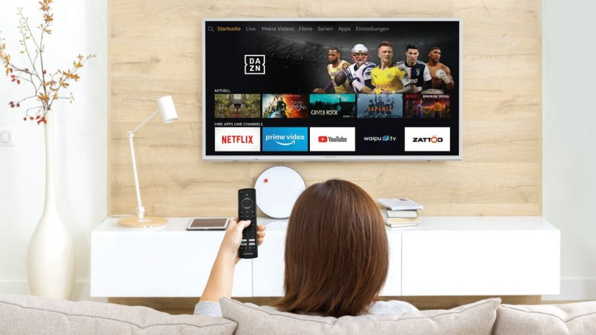 Frau sitzt vorm Fernseher und schaut auf den Amazon Fire TV