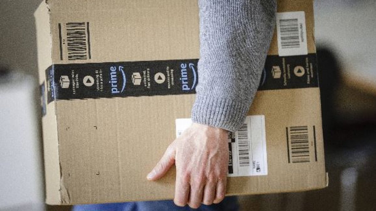 Mann mit Amazon Prime Paket in der Hand.
