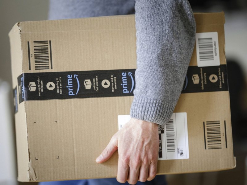Mann mit Amazon-Paket unter dem Arm