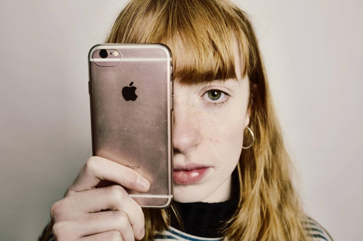 Mädchen hält iPhone sich ein iPhone vor das Gesicht