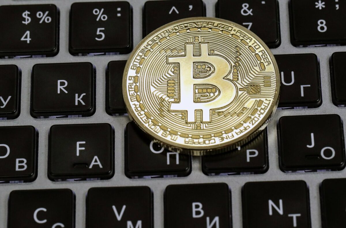 Ein Bitcoin liegt auf einer Tastatur.