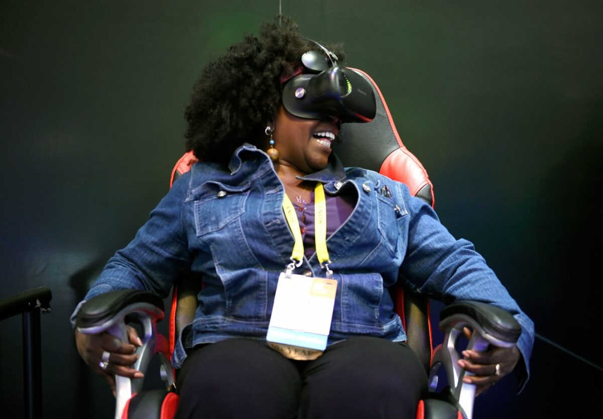 CES-Besucherin sitzt mit VR-Headset auf einem Stuhl und lacht
