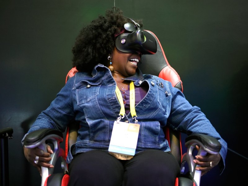 CES-Besucherin sitzt mit VR-Headset auf einem Stuhl und lacht