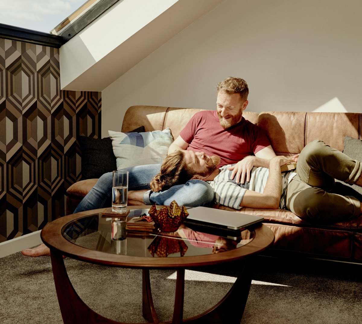 Zwei Männer sitzen in einem Luxusapartment auf dem Sofa.