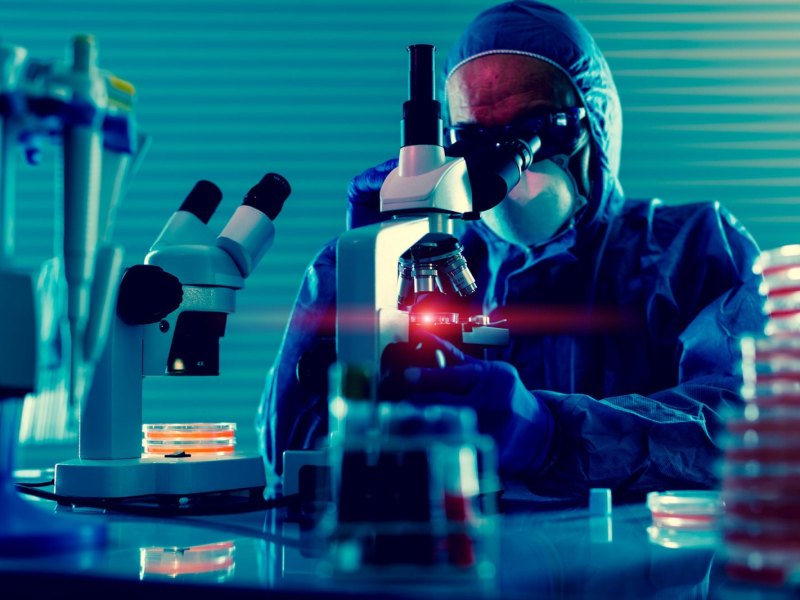 Mann im Labor mit Mikroskop.