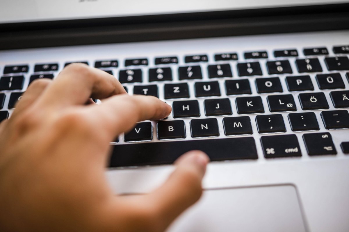 Eine Hand tippt auf der Tastatur eines Mac Books.