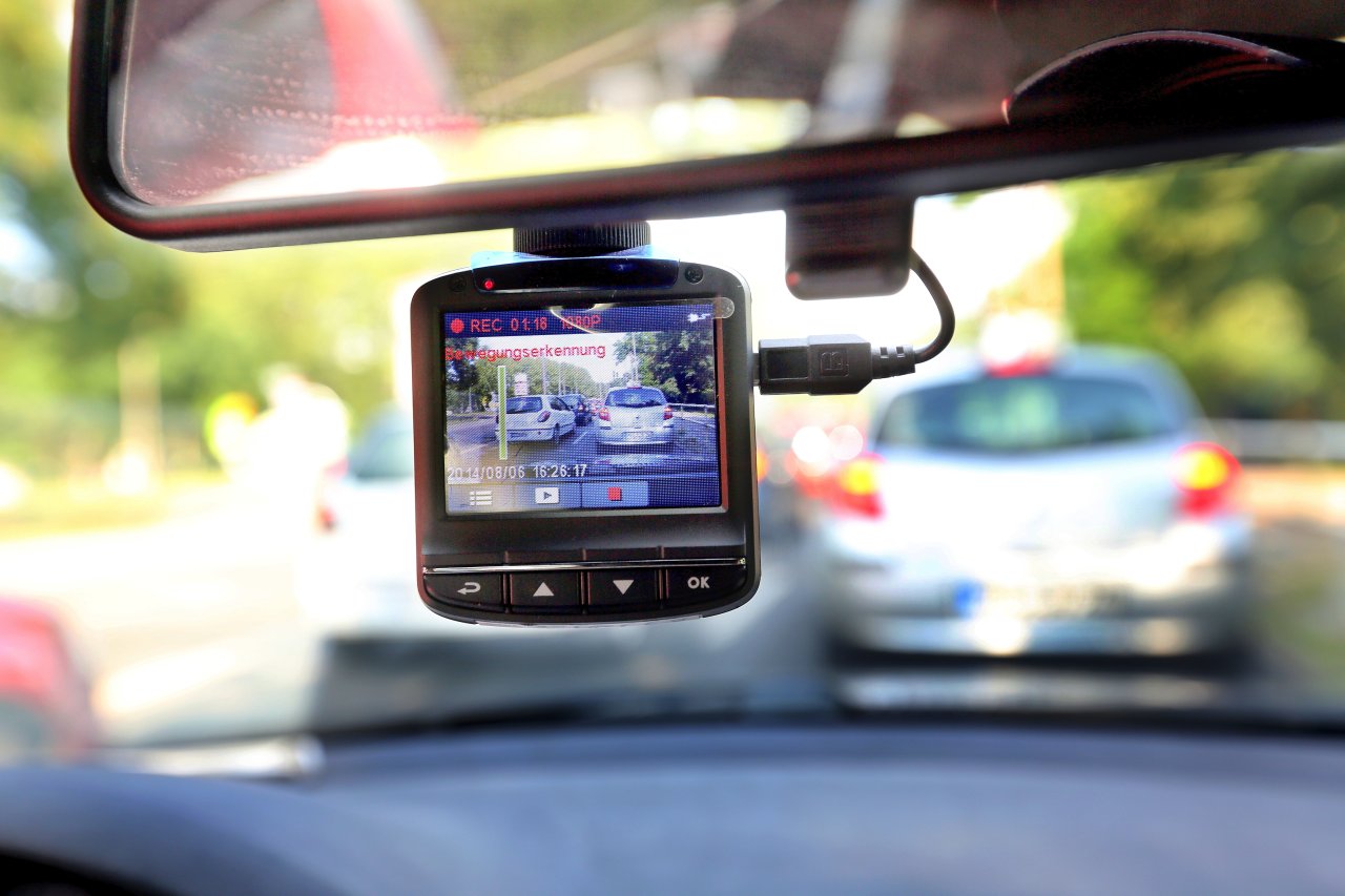 Eine sogenannte Dashcam, befestigt an der Windschutzscheibe, filmt Straßenverkehr aus einem Auto. 