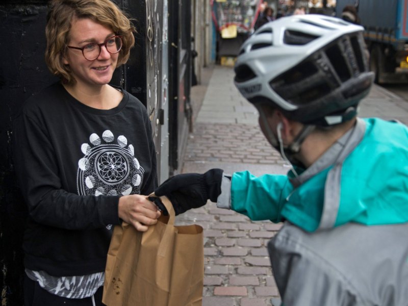 Ein Deliveroo-Fahrer beliefert eine Kundin.