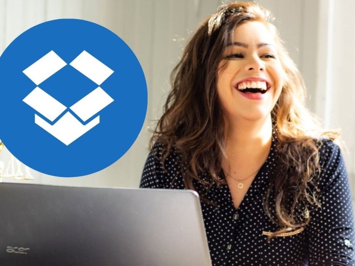 Eine Frau sitzt am Laptop und lacht. Im Vordergrund ist das Dropbox-Logo.