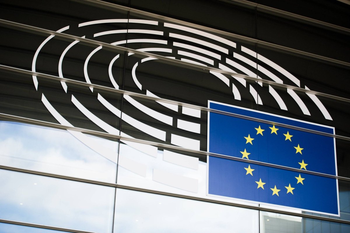 Die europäische Flagge vor dem Logo des EU-Parlaments.