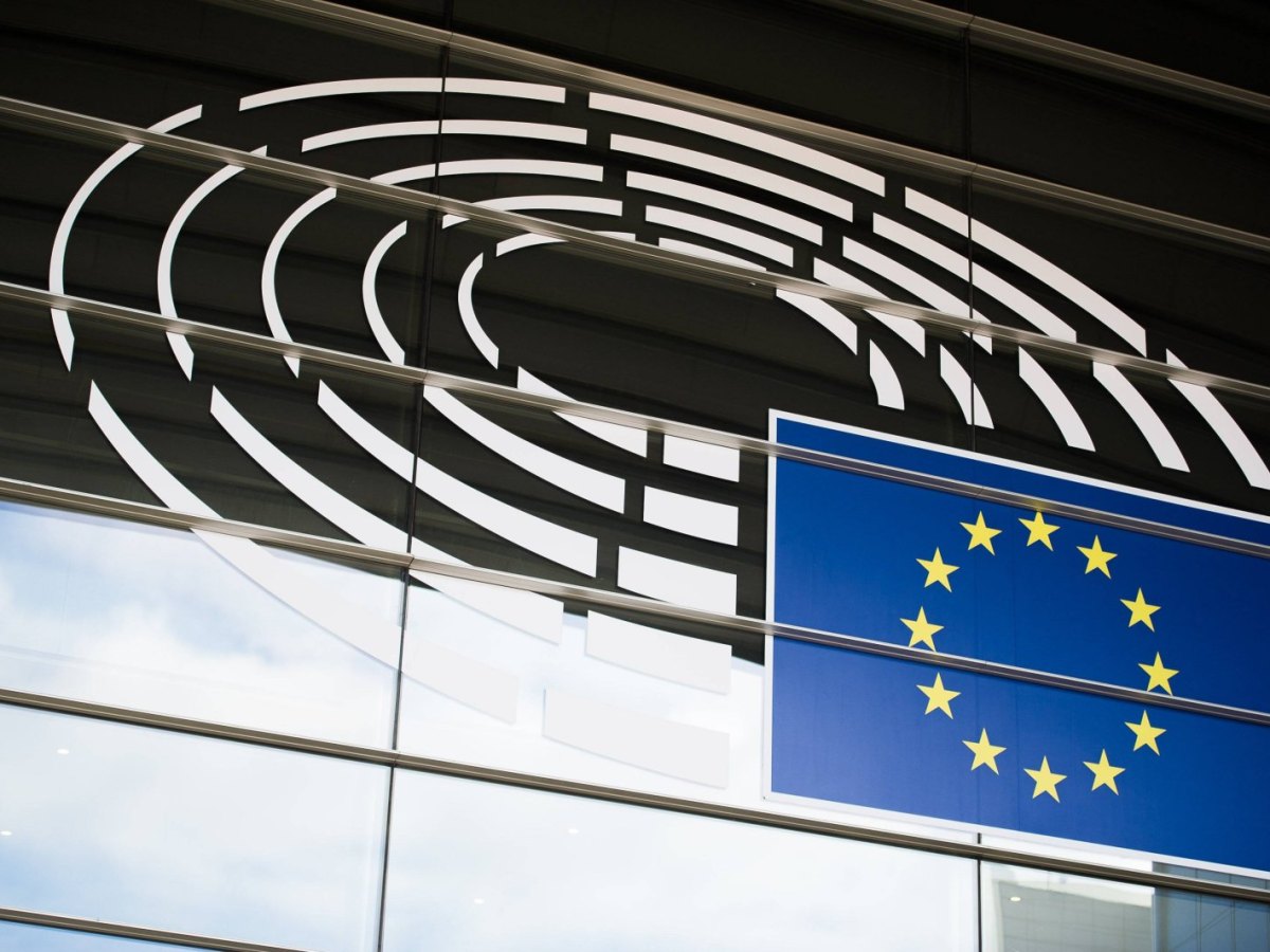 Die europäische Flagge vor dem Logo des EU-Parlaments.