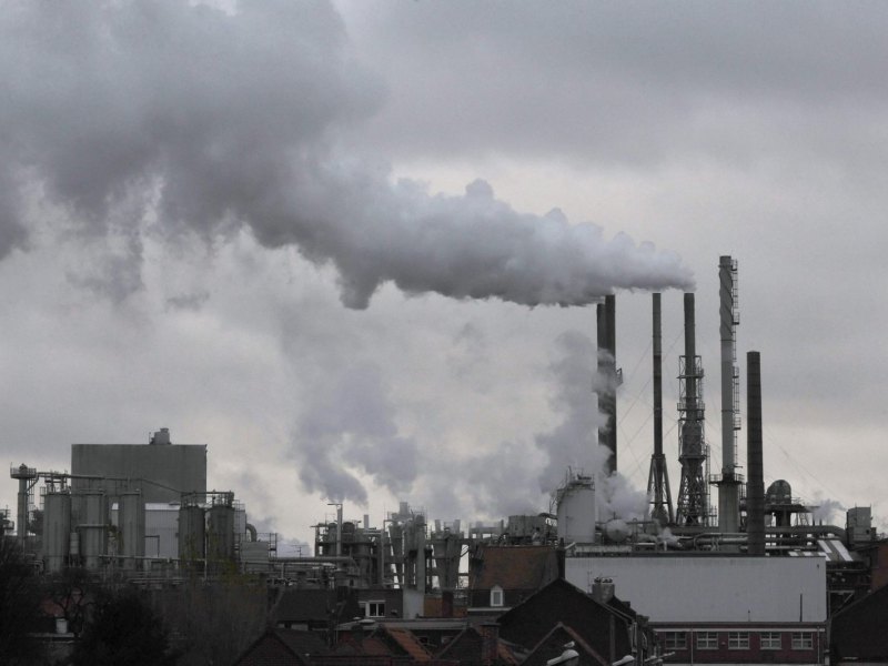 Ein Kraftwerk stößt dichten Rauch vor grauem Himmel aus.