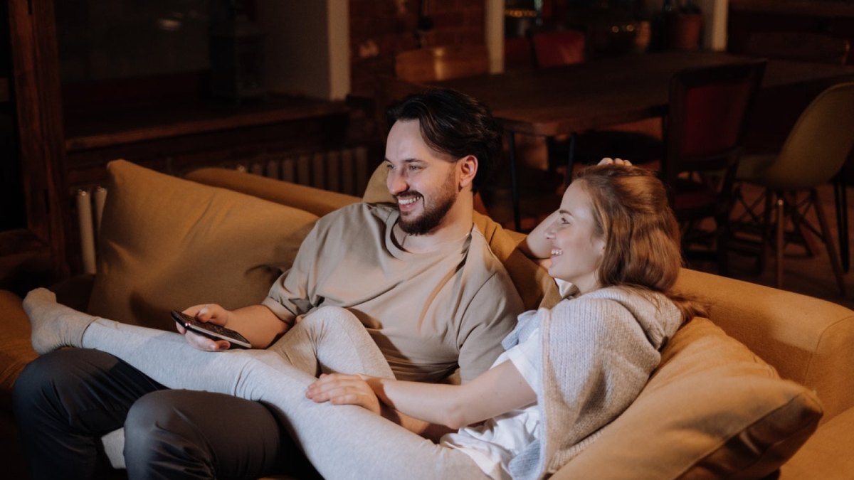 Eine Frau und ein Mann sitzen auf einem Sofa und schauen Fernsehen.