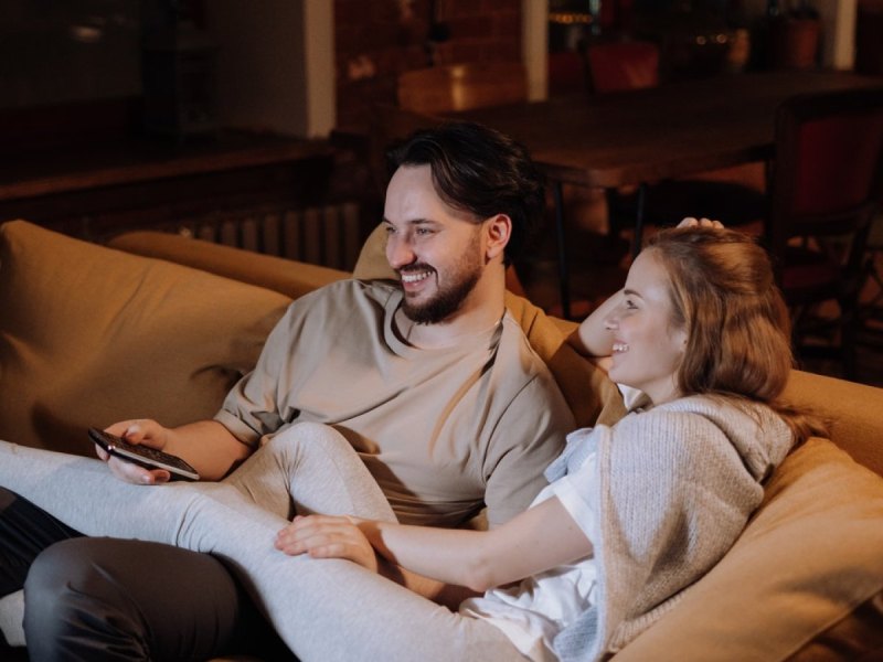 Eine Frau und ein Mann sitzen auf einem Sofa und schauen Fernsehen.