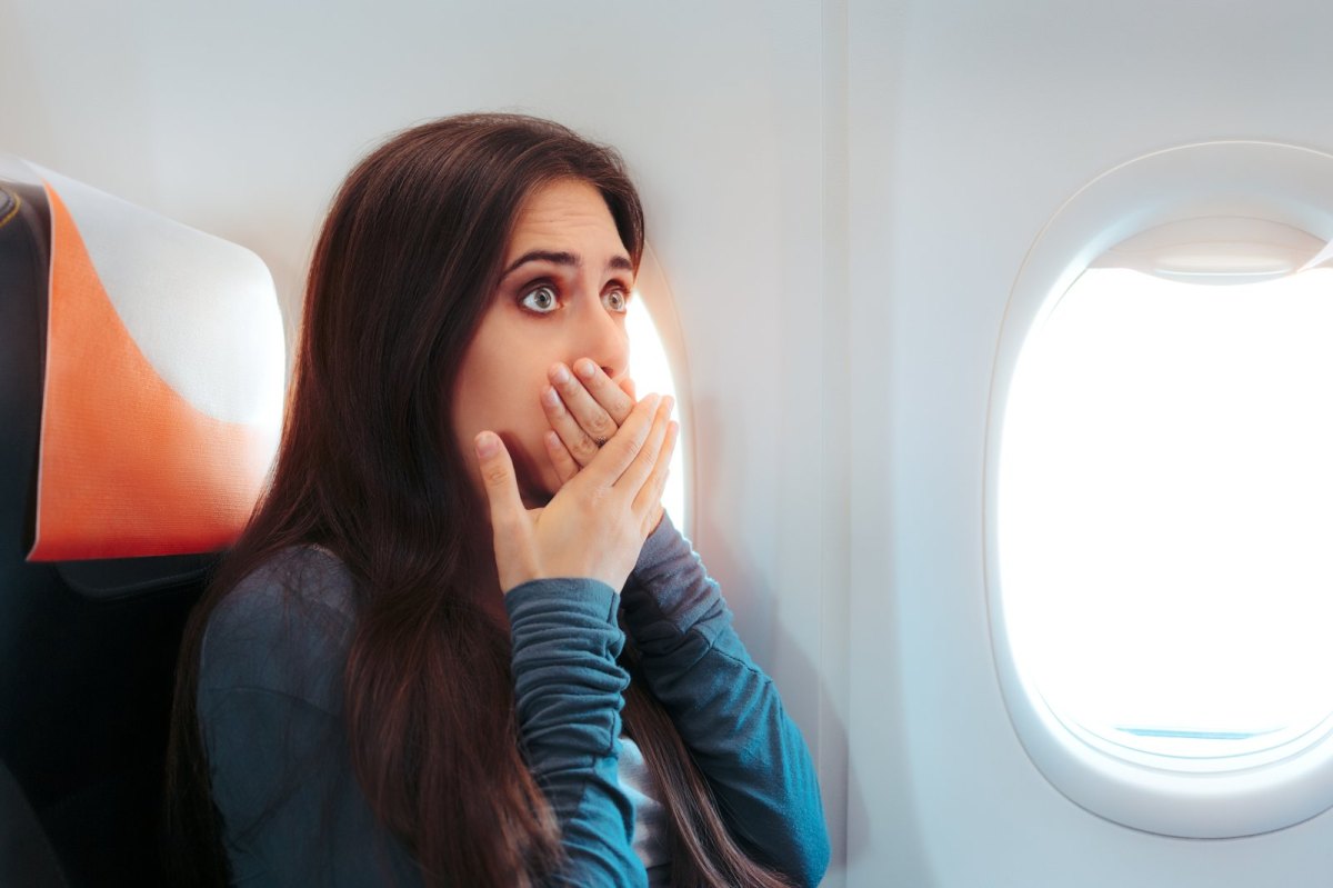 Frau schaut verängstigt im Flugzeug