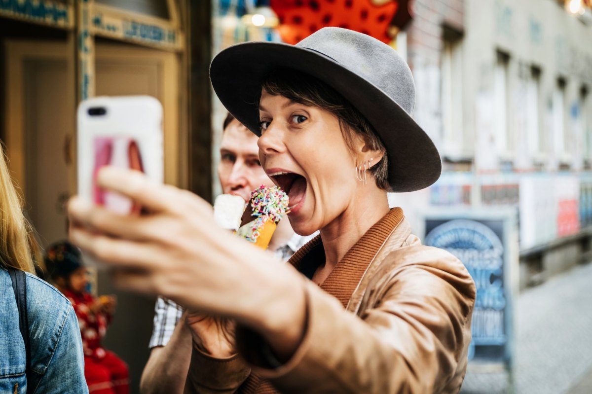 Frau macht Foto von sich mit einem Handy.