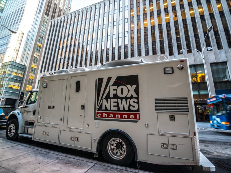 Fernsehertruck mit Fox News-Aufschrift vor einem Gebäude.