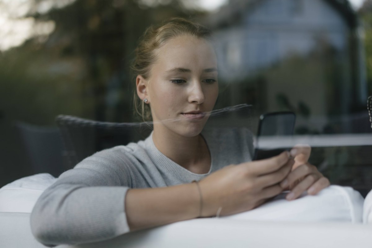 Junge Frau mit Handy auf dem Sofa