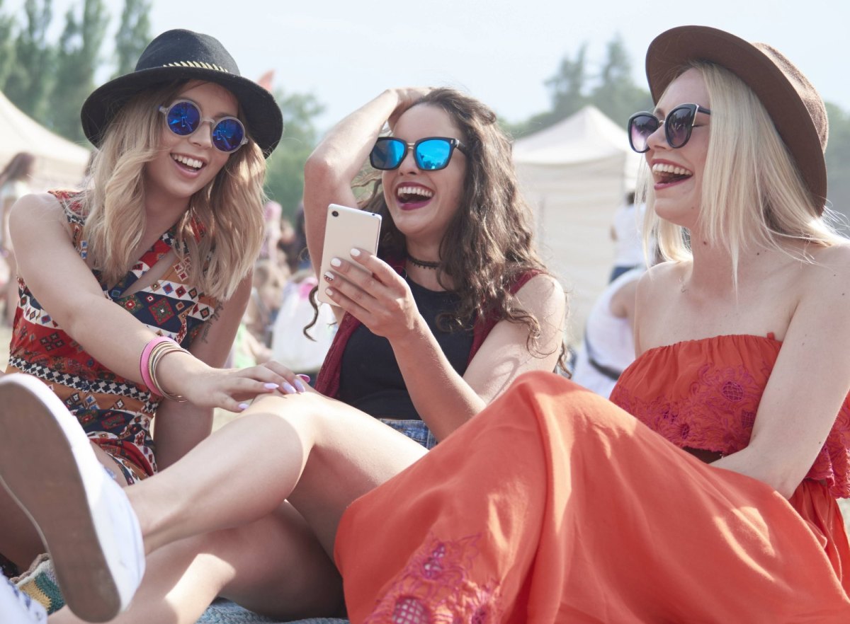 Junge Frauen auf einem Festival machen Fotos mit ihrem Smartphone.
