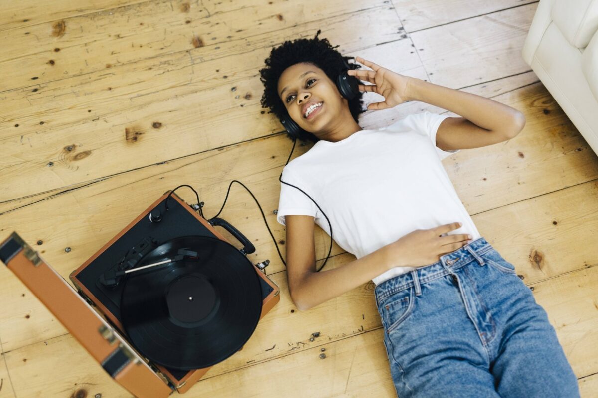 Frau liegt auf dem Boden mit Kopfhörern und Plattenspieler