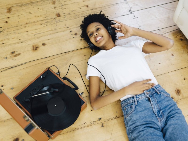 Frau liegt auf dem Boden mit Kopfhörern und Plattenspieler