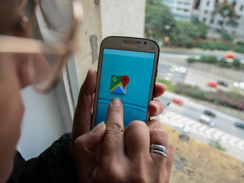 Mann nutzt Handy mit Google-Maps-Logo