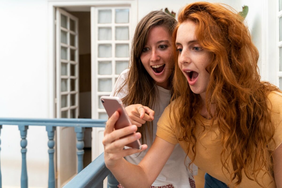 Zwei Frauen schauen überrascht auf ein Handy.
