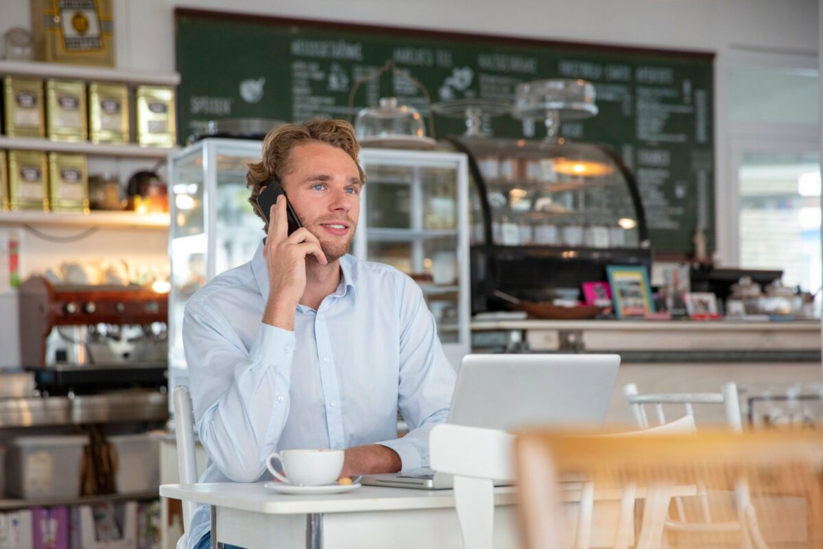 Mann sitzt im Café und telefoniert.