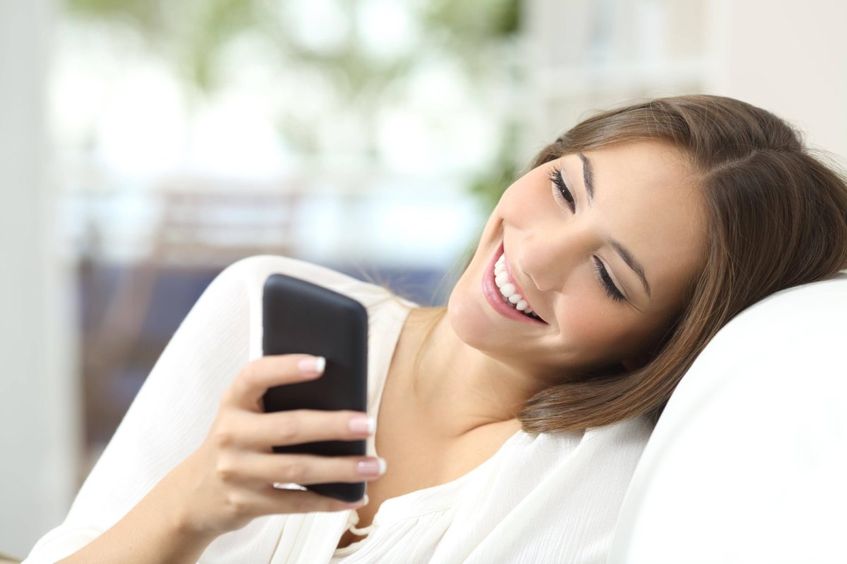 Frau schaut glücklick auf ihr Handy