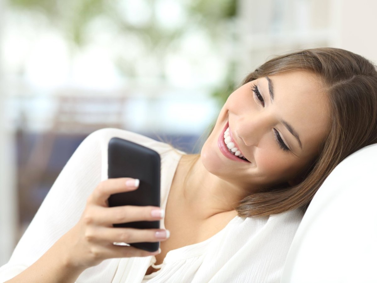 Frau schaut glücklick auf ihr Handy