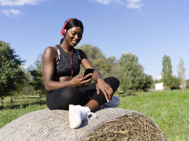 Frau in Sportoutfit mit Handy und Kopfhörern.