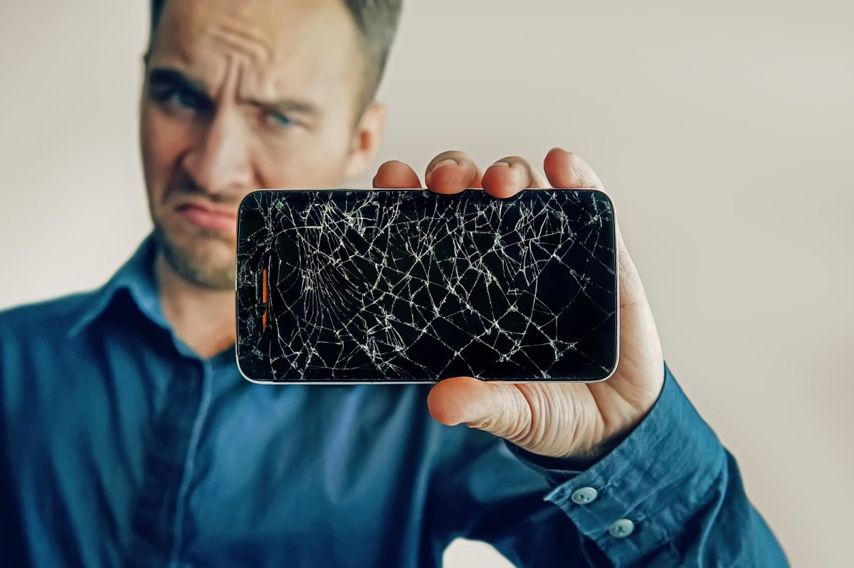 Mann hält ein Handy mit gebrochenem Display in der Hand