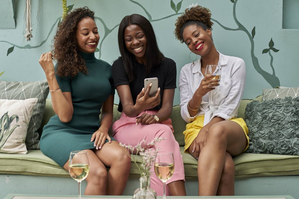 Drei Frauen schauen lachend auf ein Handy.