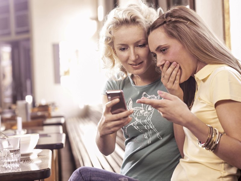 Zwei Frauen gucken auf ein Smartphone.