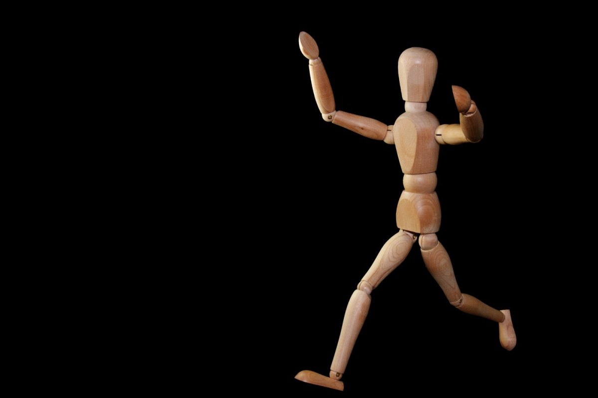 Eine Holzfigur in Menschengestalt wird im Laufen dargestellt.