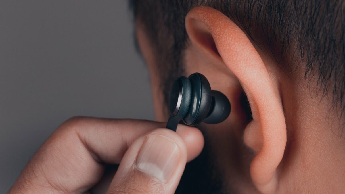 Man steckt sich In-Ear-Kopfhörer ins Ohr.