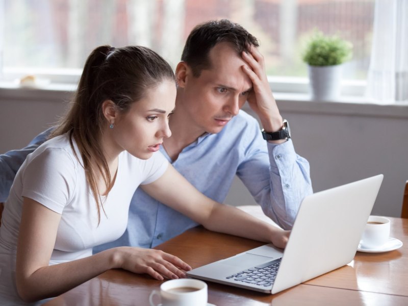 Mann und Frau starren geschockt auf einen Laptop.