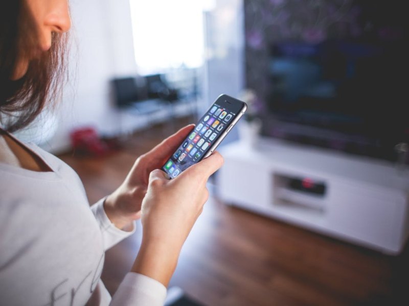 Eine Frau hält ihr iPhone in den Händen und guckt konzentriert.