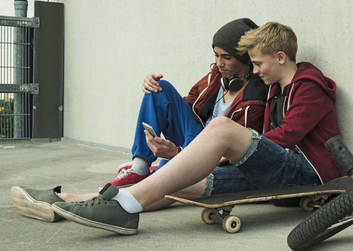 Jugendliche mit Skateboard und Smartphone