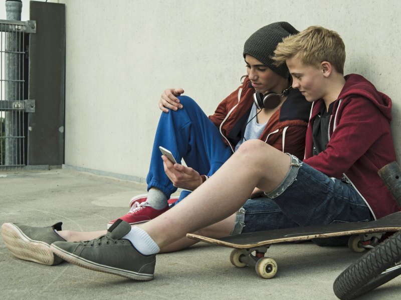 Jugendliche mit Skateboard und Smartphone