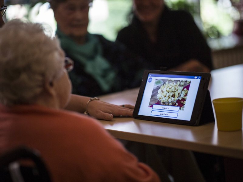 Eine ältere Dame schaut auf einen Tablet-PC.