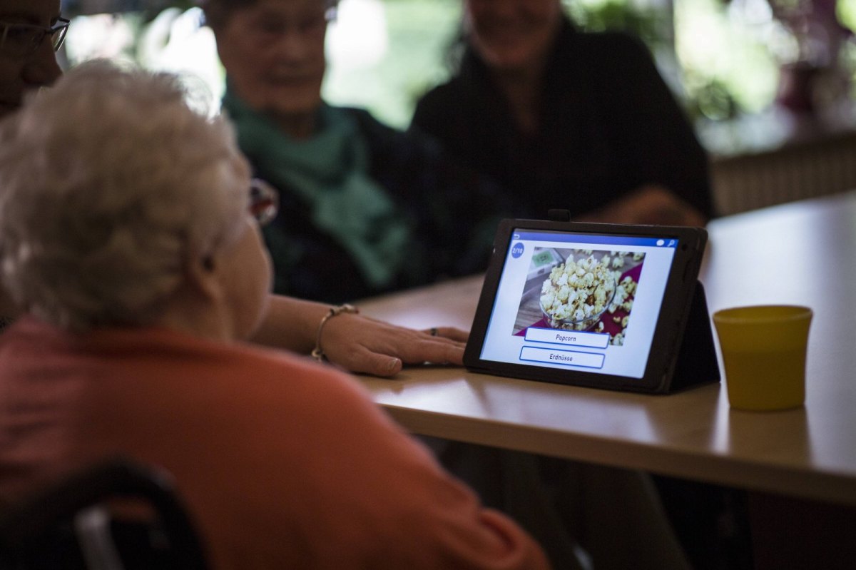 Eine ältere Dame schaut auf einen Tablet-PC.