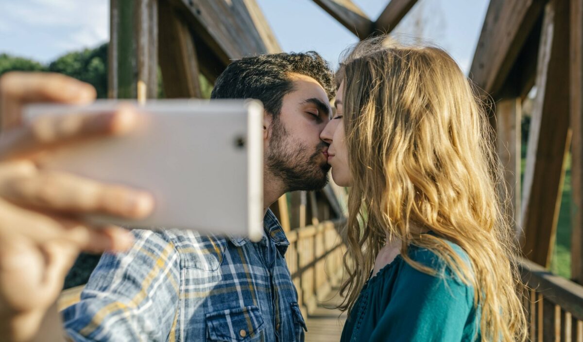 Ein küssendes Paar macht ein Selfie mit einem Smartphone.