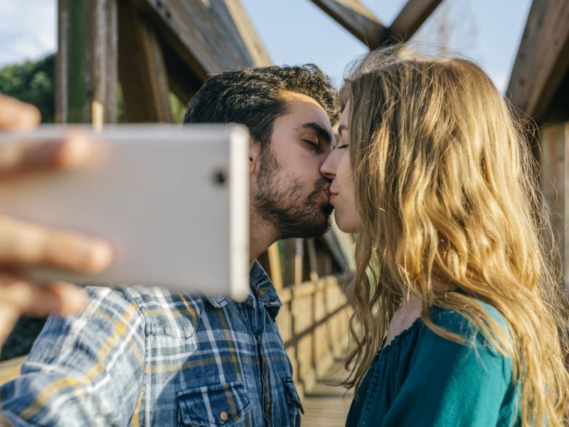 Ein küssendes Paar macht ein Selfie mit einem Smartphone.